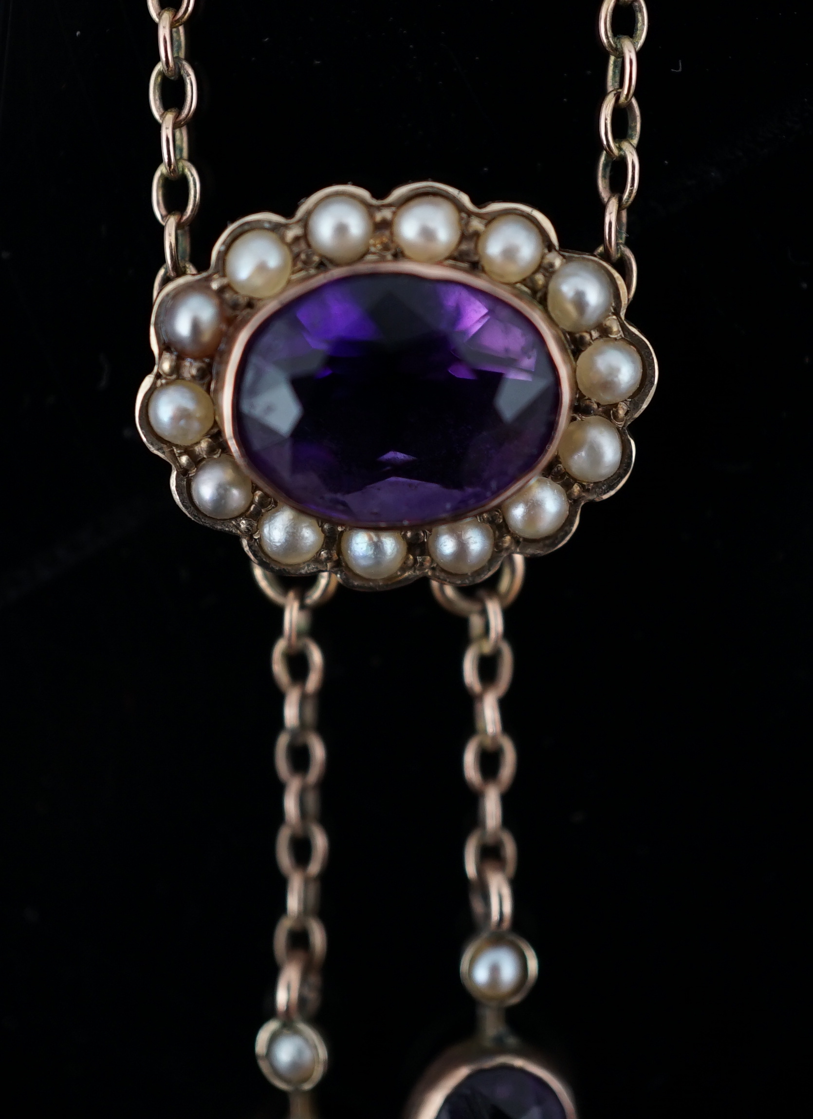 A cased Edwardian 9ct gold, amethyst and seed pearl cluster set double drop pendant necklace